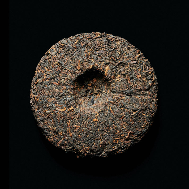 A pu erh tea cake on black background