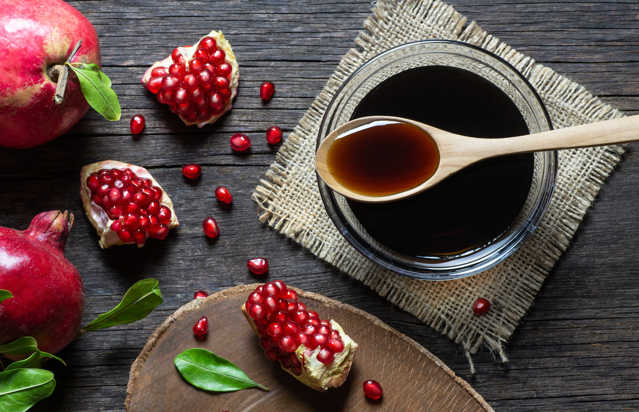Pomegranate seeds and syrup on a wooden surface
